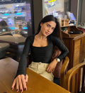 Woman sitting at a table in a restaurant with a cityscape view outside